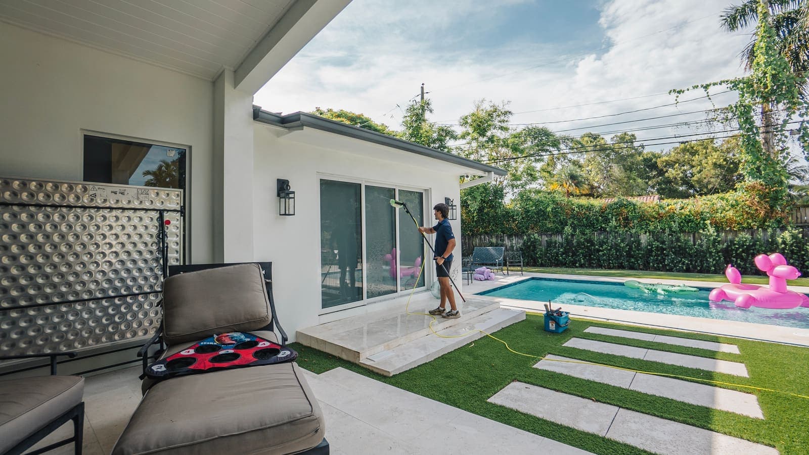 Coast technician cleaning patio sliding doors beside the pool at a Miami home