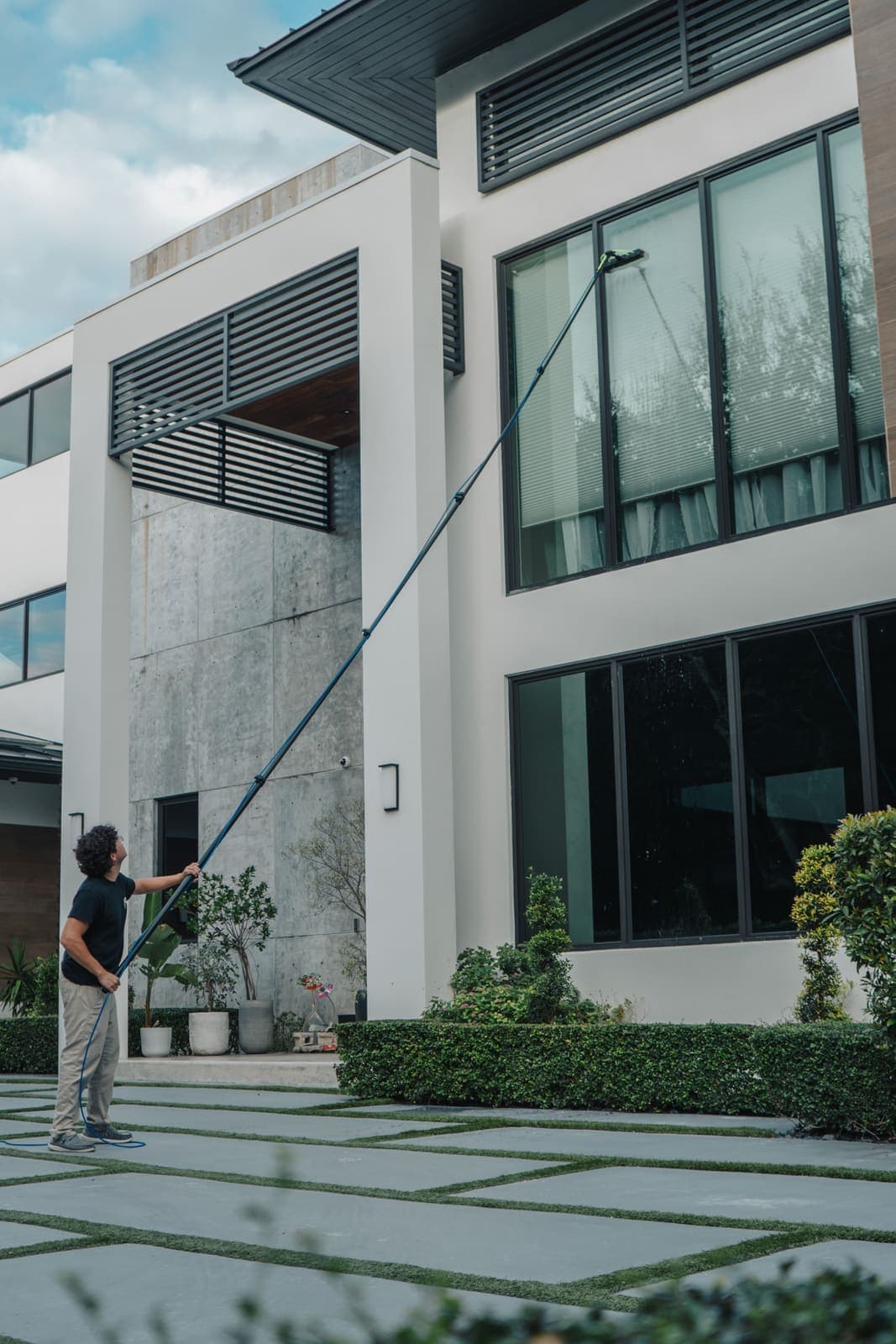 Coast technician cleaning second-story glass of a Miami home with a water-fed pole