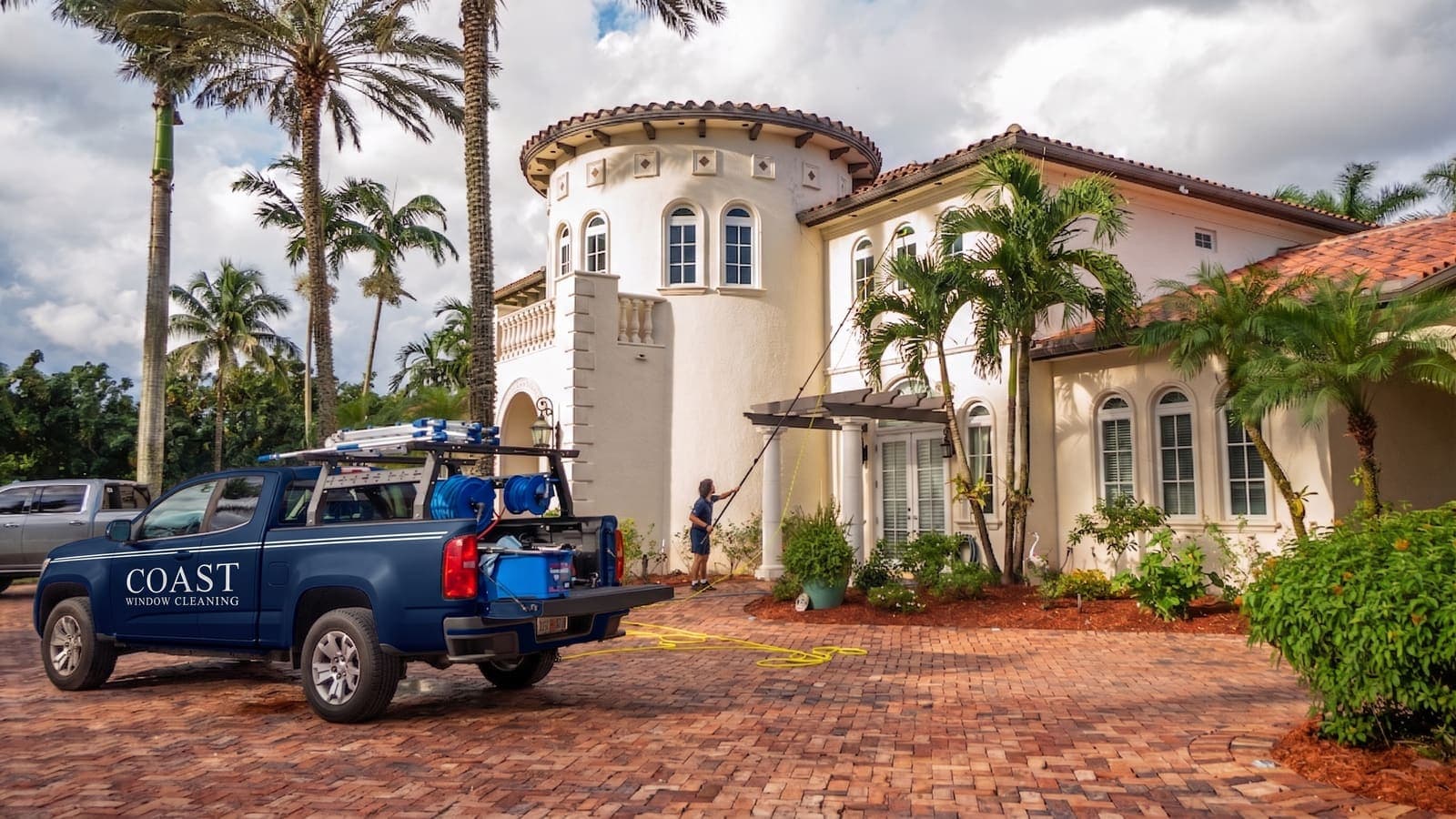 Coast truck and technician with a water-fed pole at the entry of a Mediterranean estate home