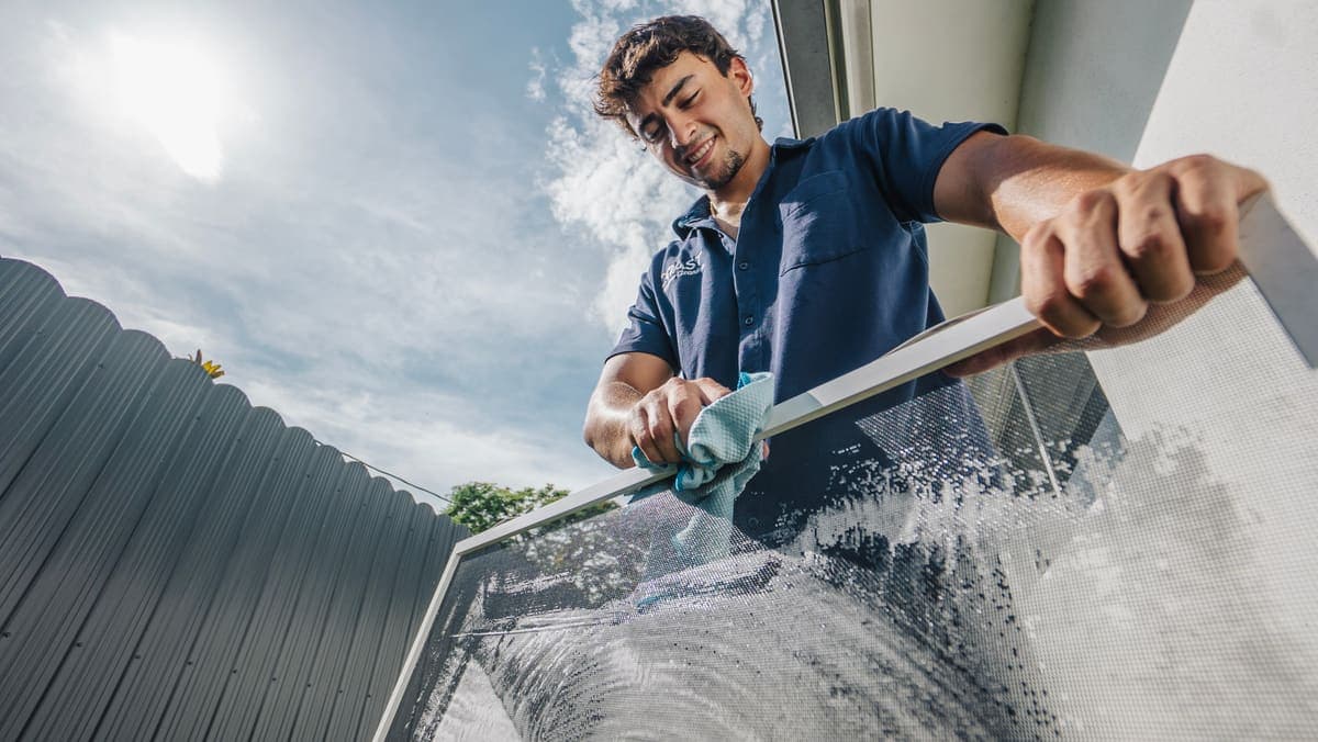 Coast technician handling a removed window screen at a Miami home