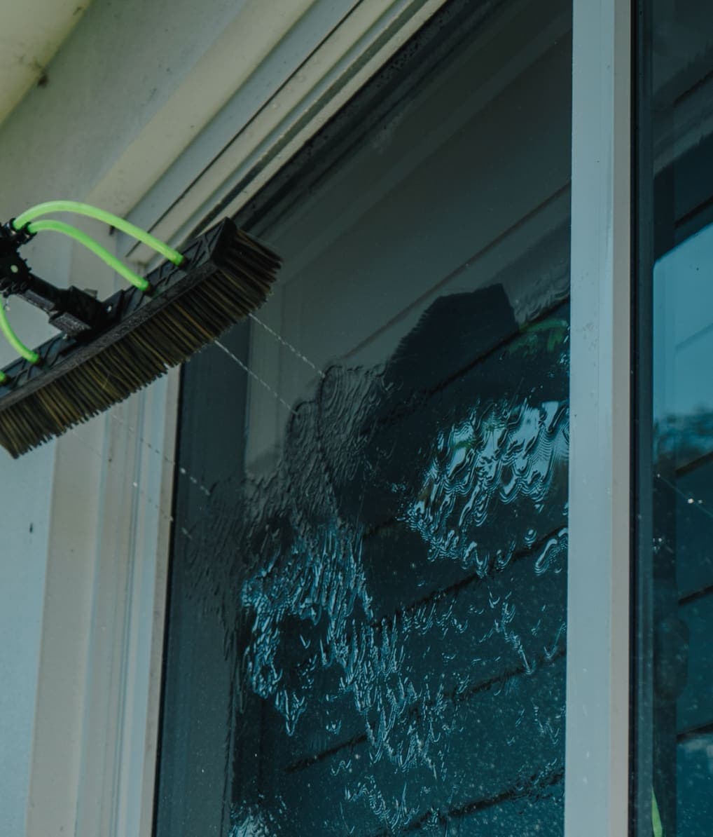 Water-fed pole rinsing a window with pure water so it dries spot-free